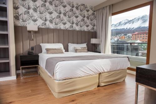 a bedroom with a large bed and a large window at Hotel Albatros in Ushuaia