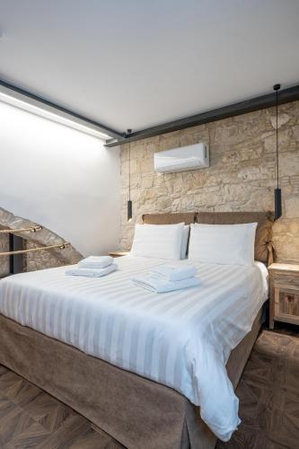 a large bed in a room with a brick wall at Palazzino Luxury Suites in Lofou