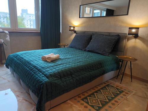 een slaapkamer met een bed met een groene deken en een spiegel bij Green apartament w Centrum in Warschau