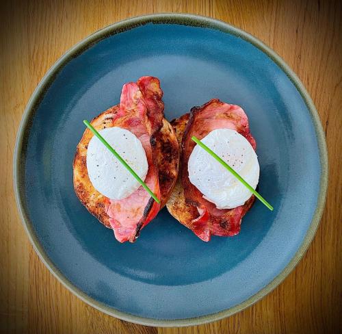 two pieces of bacon with eggs on a blue plate at Ravenscraig Guest House in Aviemore