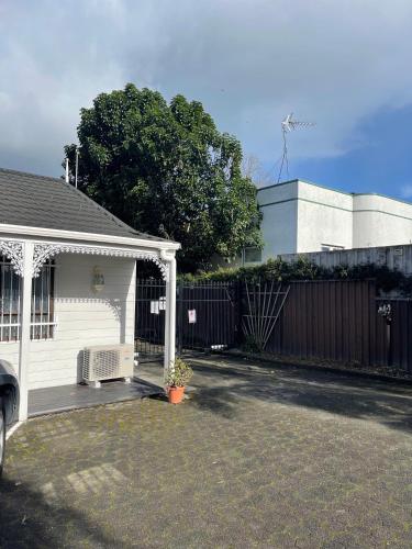 a white house with a porch and a fence at Papakura Pioneer Motor Lodge & Motel in Papakura