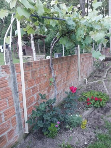 eine Backsteinmauer mit einem Baum und ein paar Blumen in der Unterkunft foresti macedo casa in Gramado