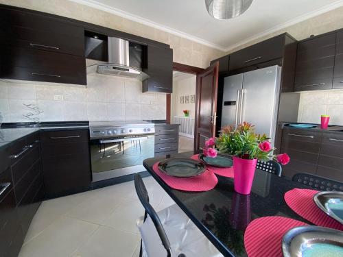 a kitchen with black cabinets and a table with flowers on it at 360 Rooftop Apartment in Dabouq in Amman