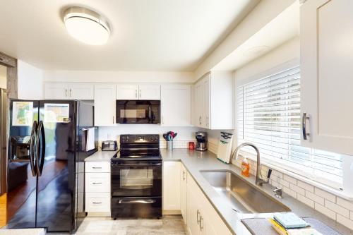 a kitchen with white cabinets and a black refrigerator at Coastal Calm in Lincoln City