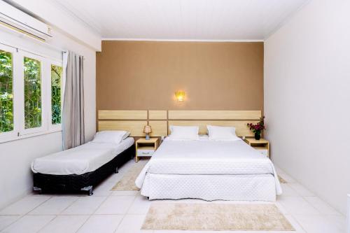 two beds in a room with two windows at Hotel SPA Paraíso in Cruzeiro do Sul