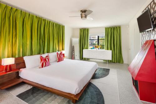 um quarto com uma cama grande e cortinas verdes em Sunset Inn and Cottages em St. Pete Beach