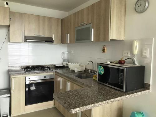 a kitchen with a microwave oven and a sink at Apartamento Duplex con vista al mar in Gaira