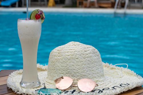 a straw hat and sunglasses and a drink on a table at Hotel Cocoliso Island Resort in Isla Grande