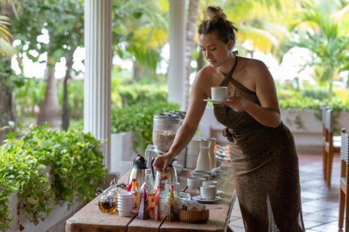 a woman in a dress holding a cup of coffee at Hotel Cocoliso Island Resort in Isla Grande