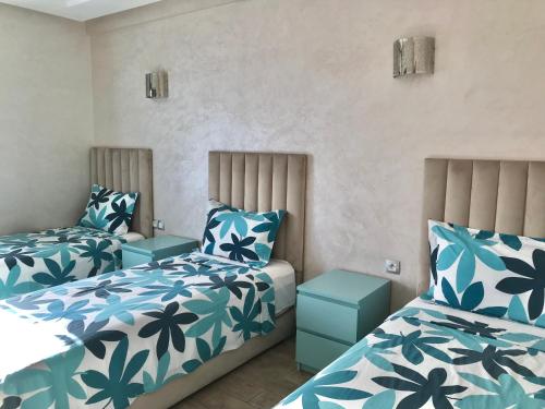 una camera con due letti con lenzuola blu e bianche di Marbella Beach location pour famille 2 chambres a Minaret de Mansuria