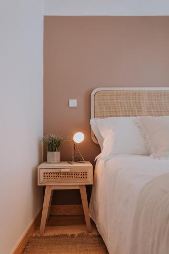 a bed with a table with a lamp on it at CasadoRioHotel in Constância