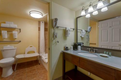 a bathroom with a toilet and a sink and a mirror at Best Western Phoenix Goodyear Inn in Goodyear