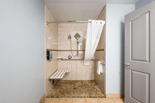 a walk in shower with a bench in a bathroom at Best Western Big Country Inn in Coalinga