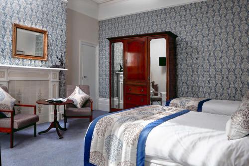 a bedroom with a bed and a chair and a mirror at The Lansdowne, Eastbourne in Eastbourne