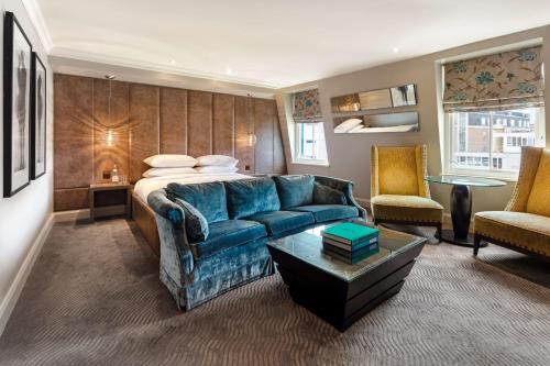 a living room with a blue couch and a bed at Radisson Blu Hotel, London Bloomsbury in London