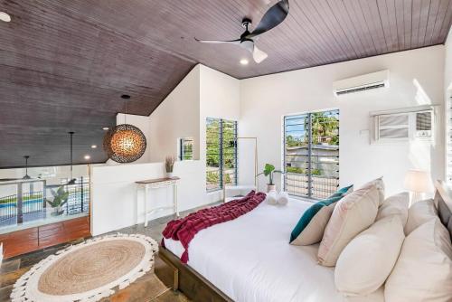 Cette chambre comprend un grand lit blanc et un ventilateur de plafond. dans l'établissement Cool by the Pool - A Private Beachside Retreat, à Fannie Bay
