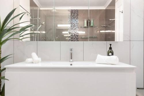 uma casa de banho branca com um lavatório e um espelho em Oceanfront Arafura Abode with Stunning Views em Nightcliff