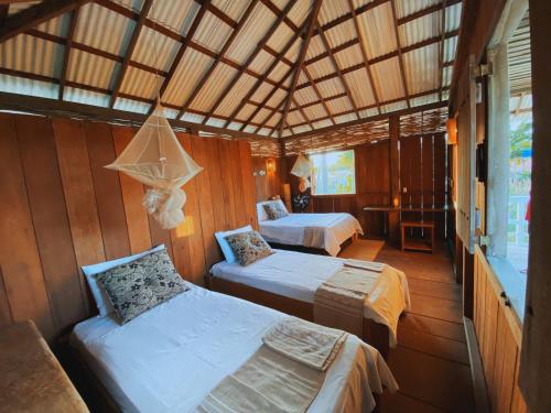 a bedroom with two beds in a wooden room at Chalés da VoVó in Atins