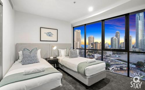 a bedroom with two beds and a large window at Avalon Apartments - QStay in Gold Coast