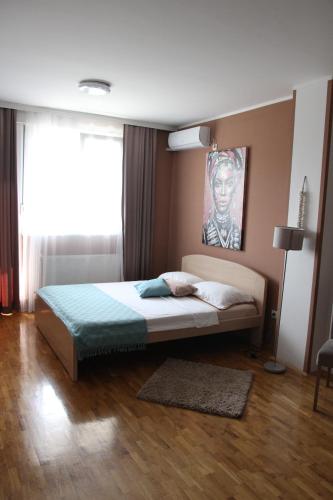 Nova PazovaにあるApartmani Elixirのベッドルーム1室(壁に絵画が描かれたベッド1台付)