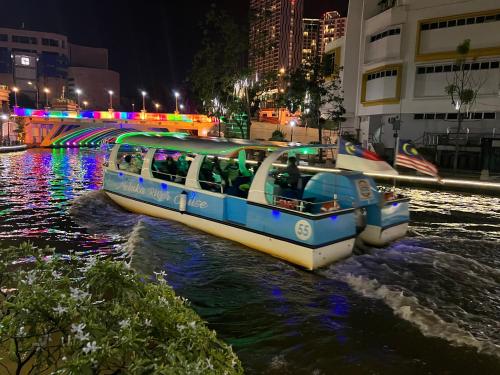 um barco azul e branco em um rio à noite em The Shore Melaka em Malaca