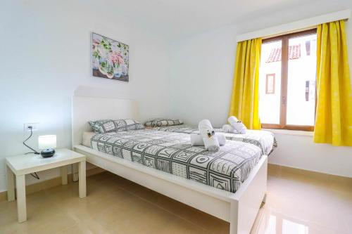 a bedroom with a bed and a window with yellow curtains at Rentaliday Garden Beach in Playa de las Americas