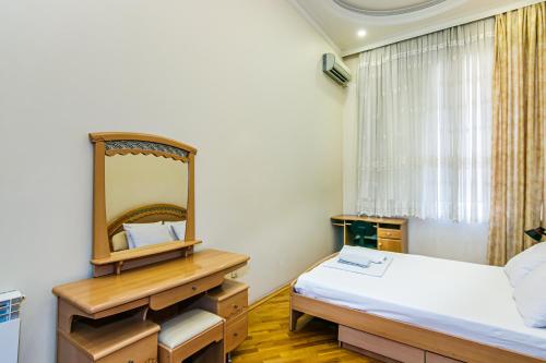 1 dormitorio con espejo, cama y escritorio en Amazing Apartment İn Center en Baku