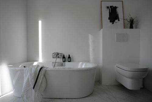 La salle de bains blanche est pourvue d'une baignoire et de toilettes. dans l'établissement Feel-good home 5 min drive from Cazaux lake & sand beaches, à La Teste-de-Buch