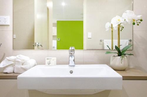 um lavatório branco na casa de banho com um espelho em Your Keys to Larrakeyah Coastal Comfort with Pool em Larrakeyah