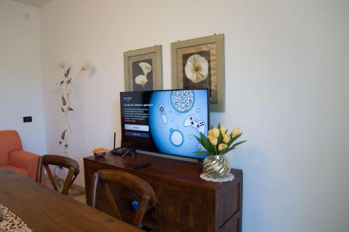 a television on a wooden table with a vase of flowers at Appartamento con giardino e parcheggio privato in Bellagio