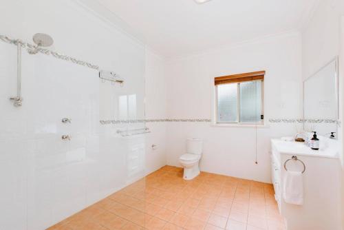 een witte badkamer met een toilet en een wastafel bij Nikki's on Market St - A Central Country Abode in Mudgee