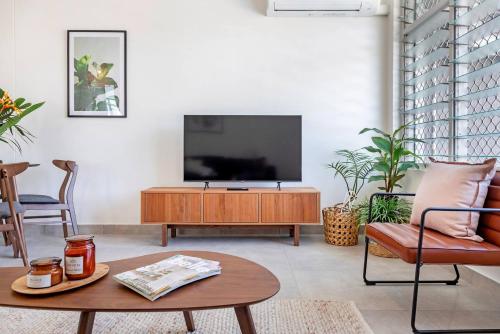 a living room with a flat screen tv on a wooden entertainment center at 'Botanica Bonita' A Stylish Nightcliff Hideaway in Nightcliff