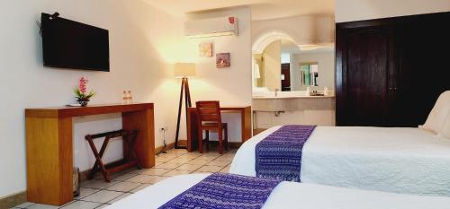 Cette chambre comprend deux lits et une télévision. dans l'établissement Hotel Boutique Plaza Doradas, à San José del Cabo