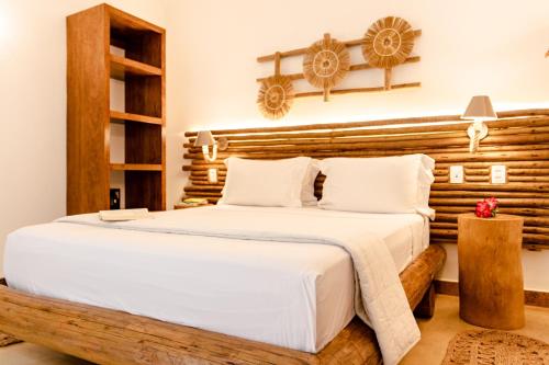a bedroom with a large bed with a wooden headboard at VillaMag in Jericoacoara