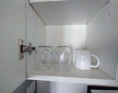 two glass mugs sitting on a shelf in a cupboard at Minicasa moderna in Castelar