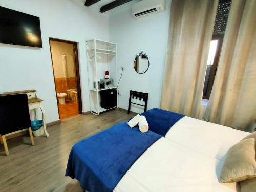 1 dormitorio con 1 cama azul y blanca y TV en Hotel Zaida, en Sevilla