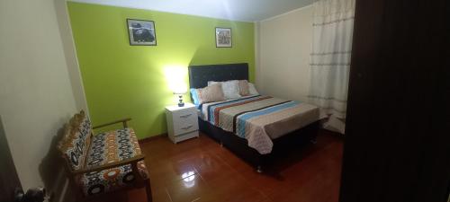 ein Schlafzimmer mit einem Bett und einer grünen Wand in der Unterkunft La Casita de Yaneth in Huancayo