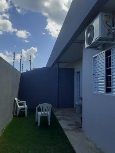 deux chaises assises sur l'herbe à l'extérieur d'une maison dans l'établissement Casa Nova confortavel e aconchegante 1, à Chapada dos Guimarães