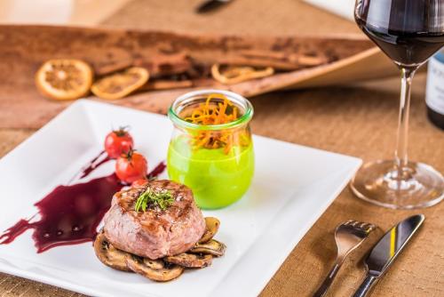 a white plate with a piece of meat and a glass of wine at Hotel Cristal Flumserberg in Flumserberg