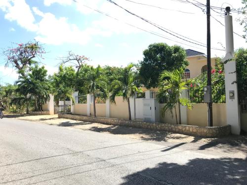 a house with a white fence and palm trees at Sommerville Resorts in Negril