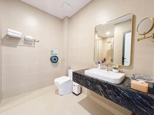 a bathroom with a sink and a mirror and a toilet at Lam's Beach Homestay in Phan Thiet