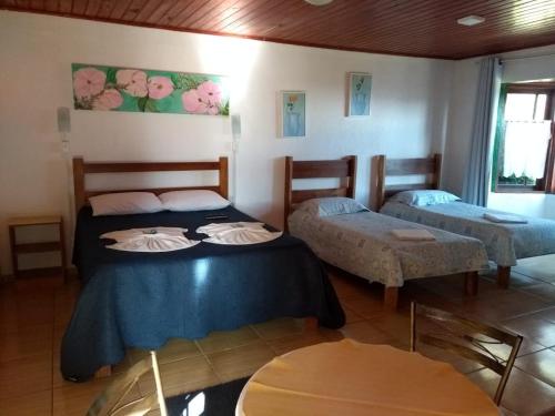 a room with two beds and a table at Pousada Por Do Sol chalés in Monte Verde