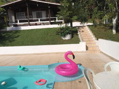 a pink swan in a pool in a backyard at Linda Chácara com Piscina in Arujá