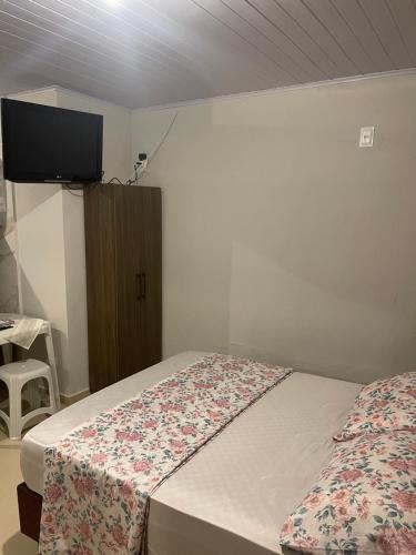 a bedroom with two beds and a tv on the wall at Itapema Suítes in Itapema