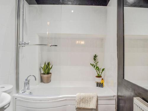 a white bathroom with a tub and a sink at The Eaves At 153 in Aberdeen