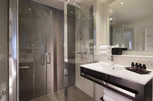 een badkamer met een glazen douche en een wastafel bij Hotel Elysees 8 in Parijs