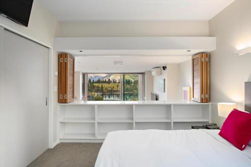 een slaapkamer met een wit bed en een raam bij Manaru Villa in Queenstown