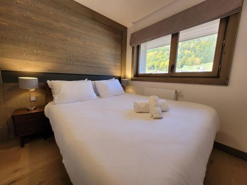 un grand lit blanc dans une chambre avec une fenêtre dans l'établissement Appartement lumineux 3 chambres, centre Les Gets, Netflix, parking, wifi - FR-1-598-112, aux Gets