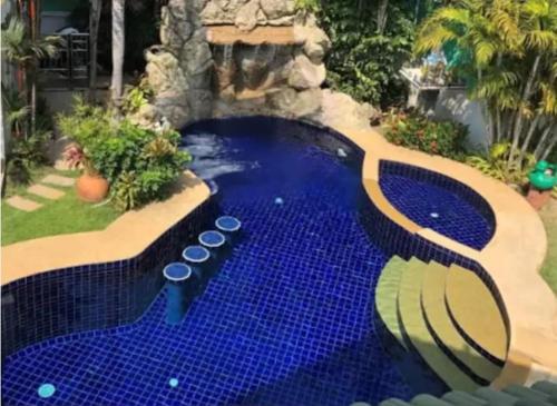 a swimming pool with blue tiles in a backyard at Private Pattaya Resort in Nong Prue