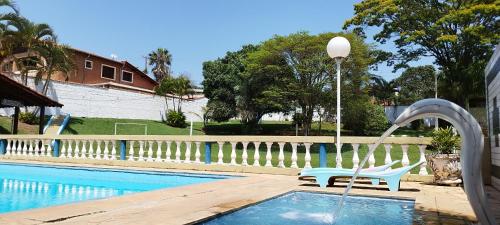 a swimming pool with a fountain and a chair next to it at Chácara Sorriso 1 em Atibaia in Atibaia